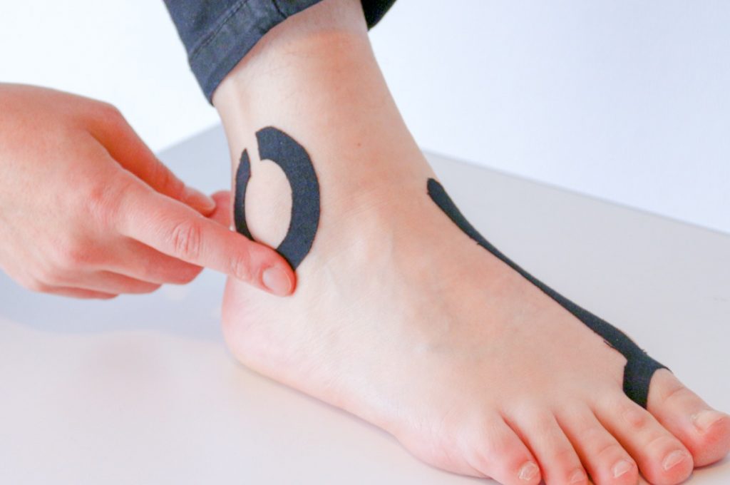 The finished Swatch applied on a human foot in the form of sport tapes. The right hand touches the tape as if it operates it as a touch wheel